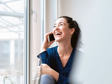 Frau sitzt telefonierend am Fenster