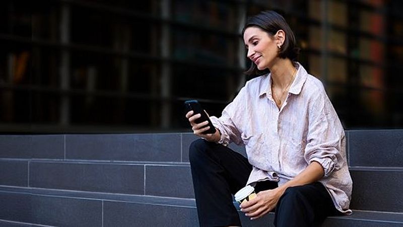 Frau sitzt auf Treppe mit Smartphone in der Hand