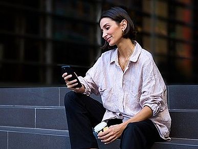 Frau sitzt auf Treppe mit Smartphone in der Hand