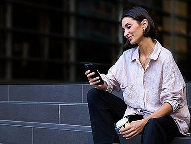 Frau sitzt auf Treppe mit Smartphone in der Hand