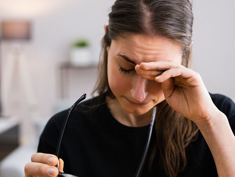 Eine Frau hält sich den Kopf vor Kopfschmerzen