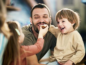 lachender Mann mit Familie beim essen